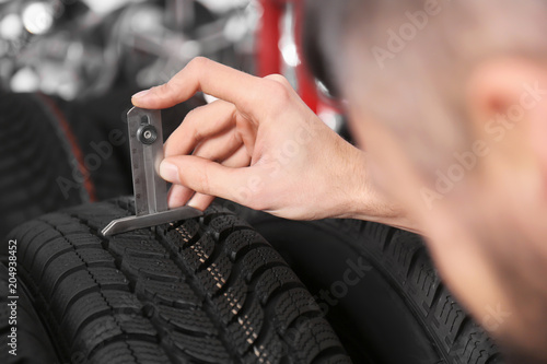 Mechanic measuring tire tread depth in automobile service centre