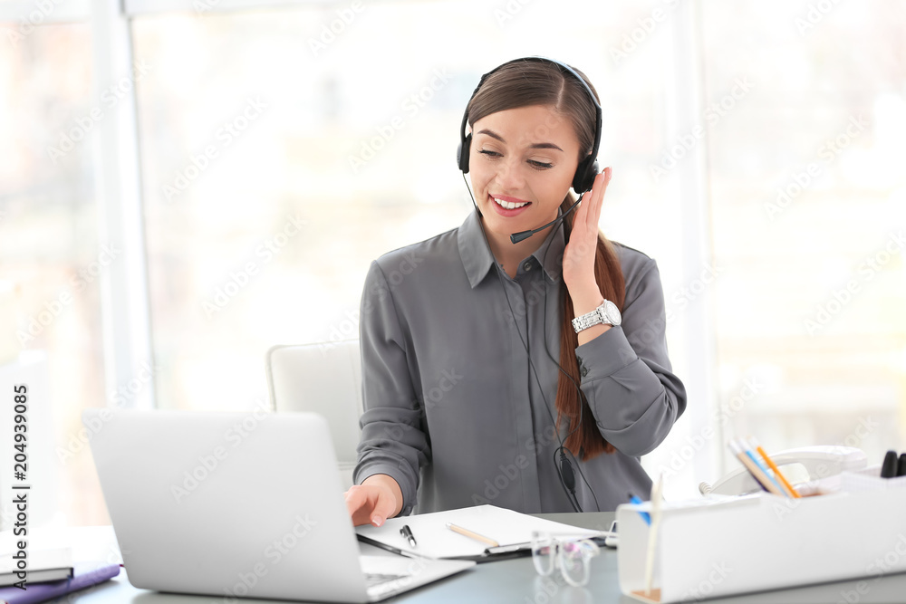 Young woman talking on phone through headset at workplace Young woman talking on phone through headset at workplace