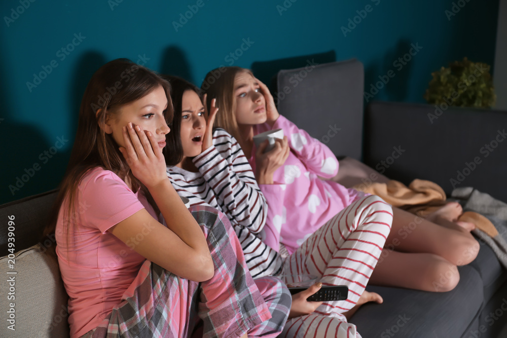 Naklejka premium Young women watching movie at home in evening
