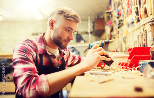 profession, carpentry, woodwork and people concept - carpenter working with wood plank at workshop