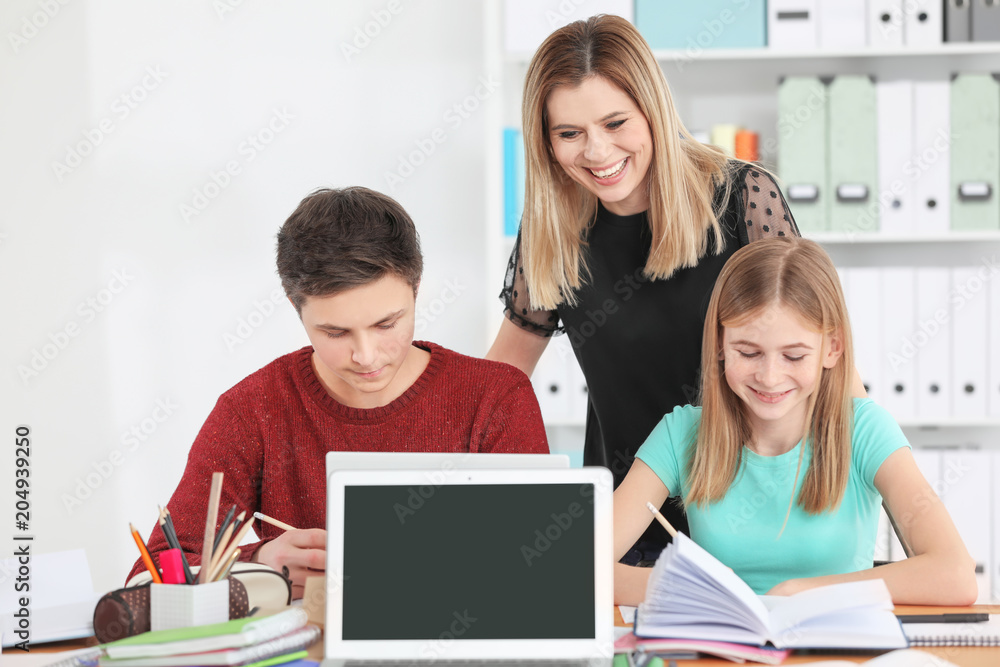 Group of teenagers doing homework with teacher in classroom Group of teenagers doing homework with teacher in classroom