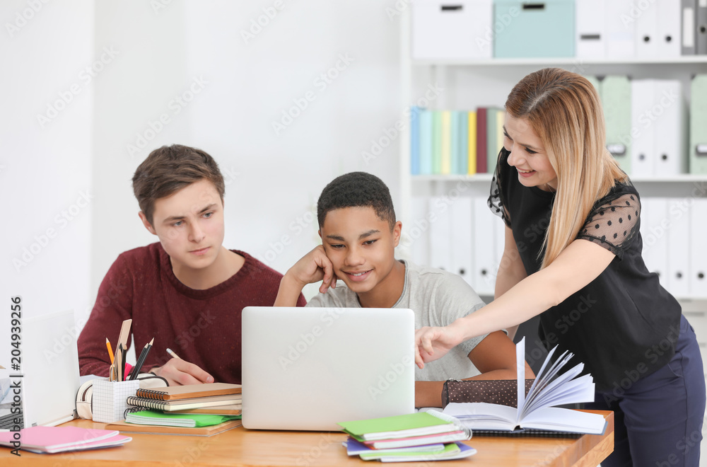 Group of teenagers doing homework with teacher in classroom Group of teenagers doing homework with teacher in classroom