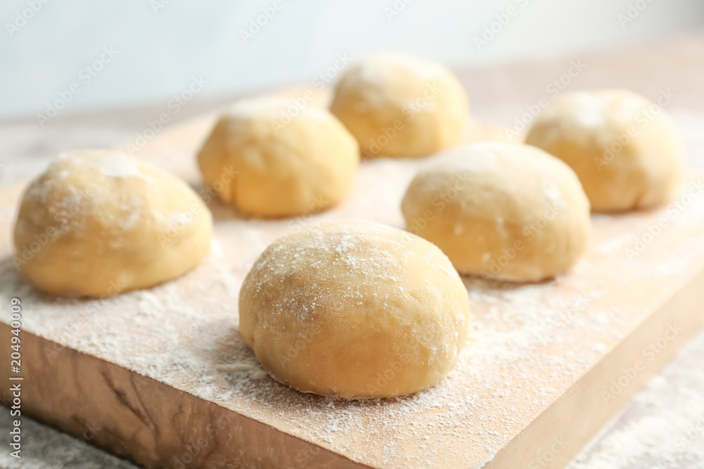 Fresh raw dough with flour on wooden board