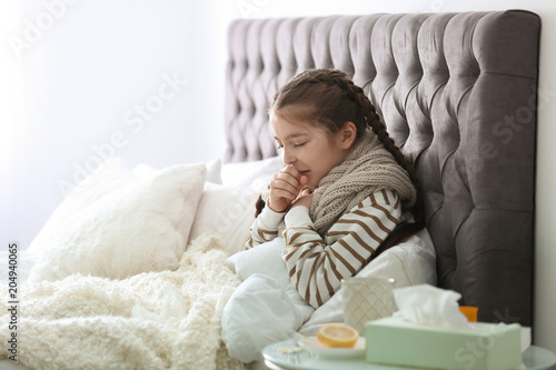 Foto Sick little girl with cough suffering from cold in bed