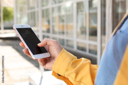Young woman using phone outdoors on sunny day