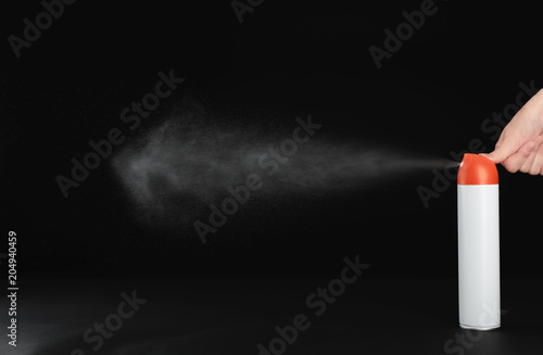Woman spraying air freshener on black background, closeup
