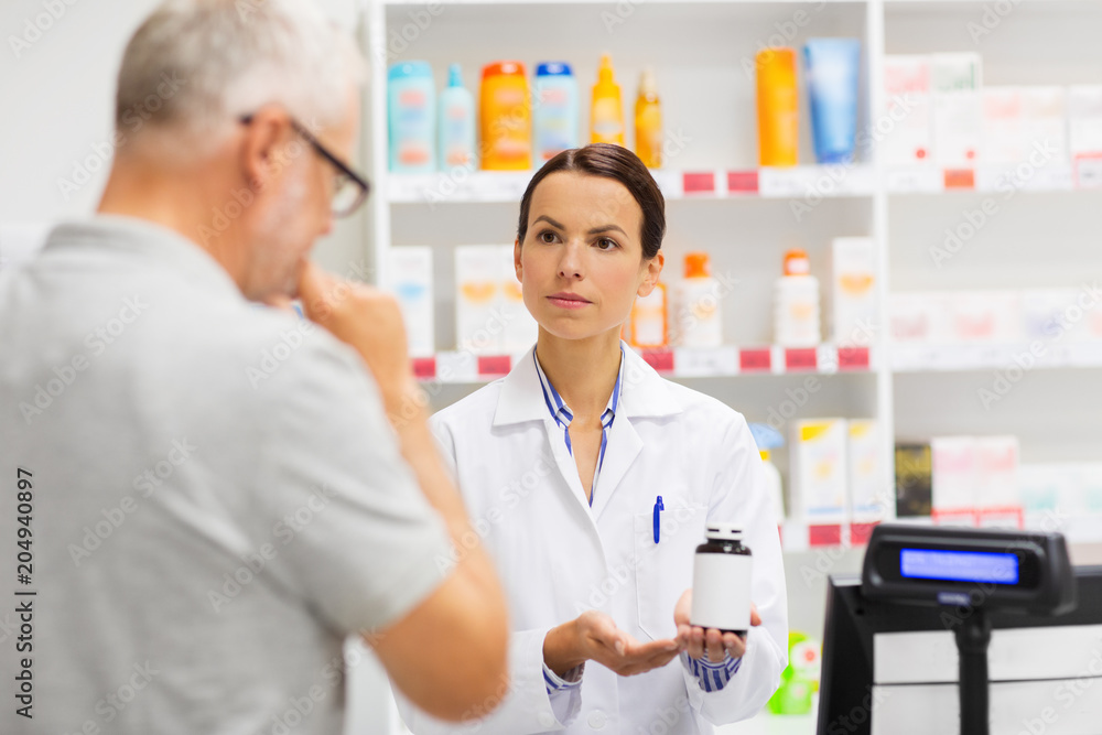 Obraz premium medicine, pharmaceutics, health care and people concept - apothecary showing drug to senior man customer at drugstore