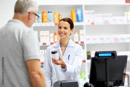 medicine, pharmaceutics, healthcare and people concept - apothecary and senior male customer buying drug at drugstore