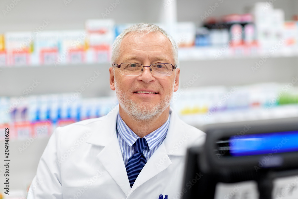 medicine, healthcare and people concept - senior apothecary at pharmacy cash register