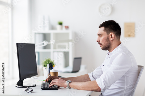business, people and technology concept - businessman typing on computer keyboard at office