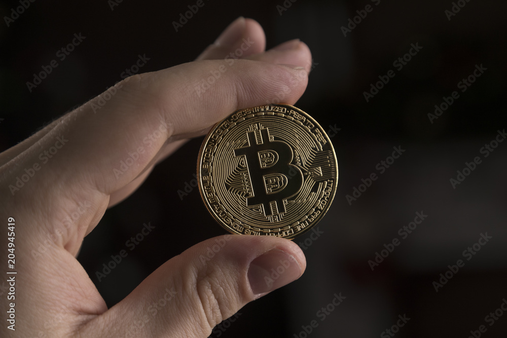 A man holding a silver bitcoin on black background A man holding a silver bitcoin on black background