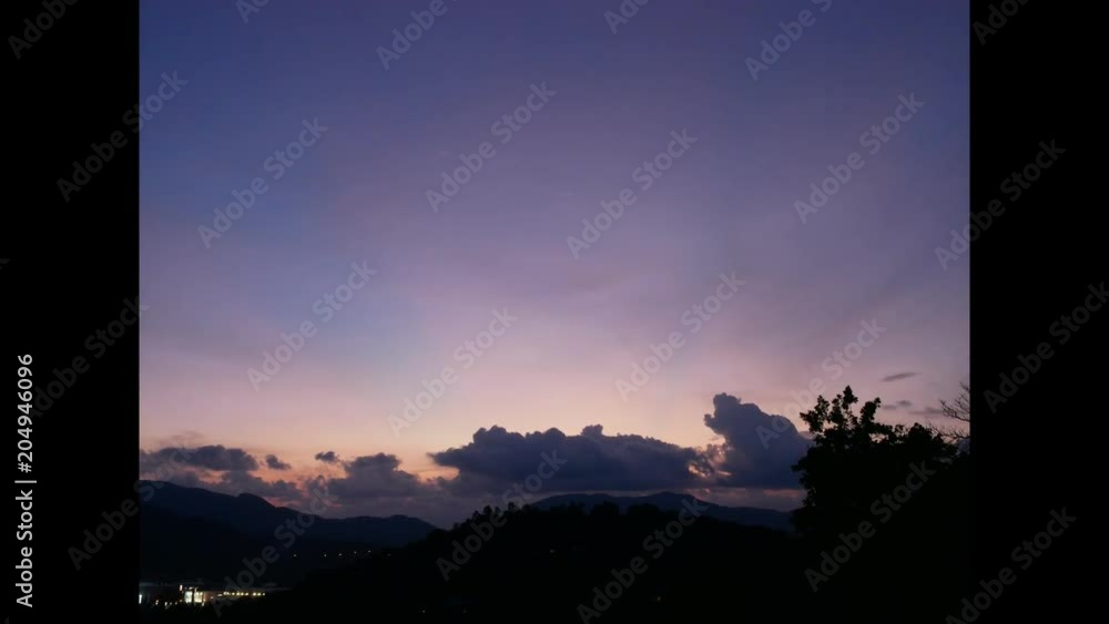 clouds moving over high silhouette mountains in evening twilight blue sky background after sunset and sunbeam light in sky. moving branch tree. View from hilltop viewpoint at Rung Hill or Khao Rung clouds moving over high silhouette mountains in evening twilight blue sky background after sunset and sunbeam light in sky. moving branch tree. View from hilltop viewpoint at Rung Hill or Khao Rung