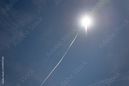 Fotografie intercontinental missile exploding in bright blue sky with smoke trail behind it