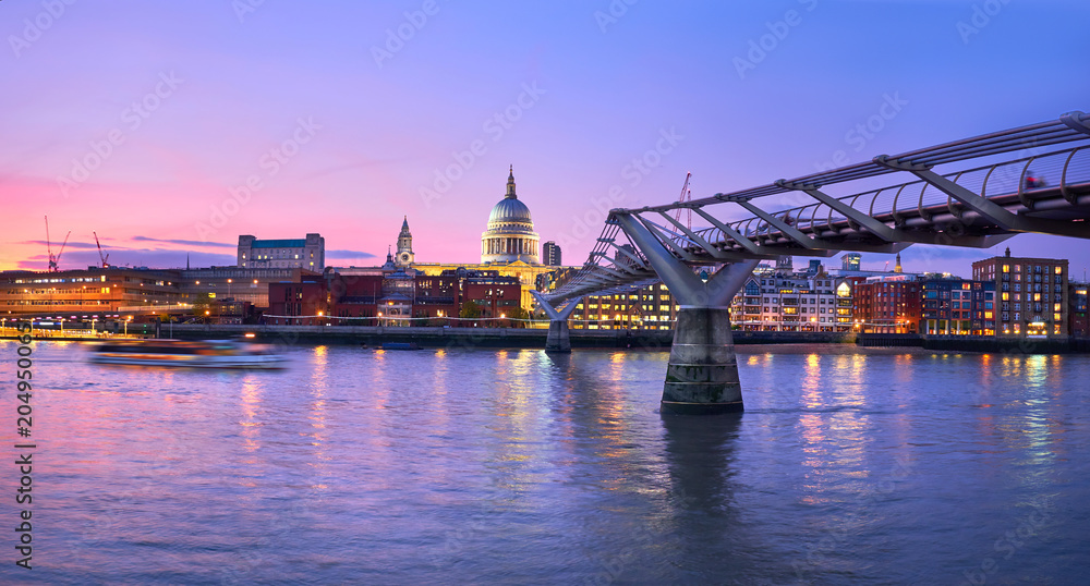 London at sunset, Millennium bridge leading towards illuminated St. Paul cathedral over Thames river