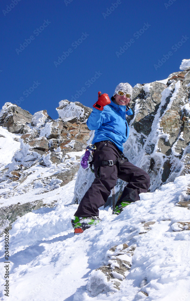 Φωτογραφία male backcountry skier hiking to a high alpine summit in Switzerland along a roc