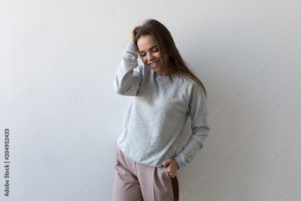 Beautiful woman in gray sweatshirt stands on white background. Mock-up. Beautiful woman in gray sweatshirt stands on white background. Mock-up.