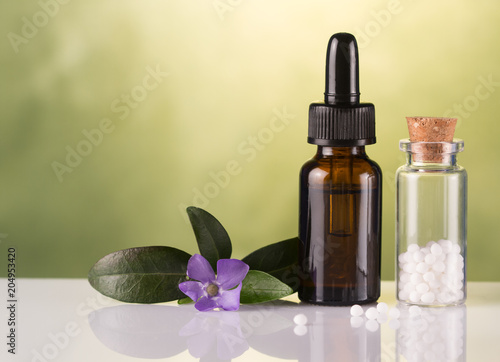 Bottle of homeopathic globules,homeopathic remedies and flowers
