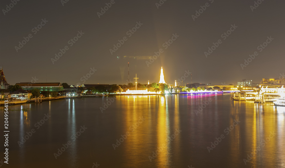 View of Wat Arun at night, beautiful lights and water traffic.
