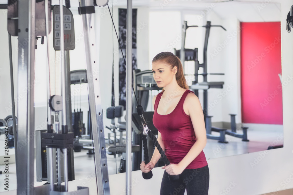 Attractive sporty girl doing extension of hands on the block at the gym. Glad pretty girl is enjoying with her training process. Sport concept. Attractive sporty girl doing extension of hands on the block at the gym. Glad pretty girl is enjoying with her training process. Sport concept.