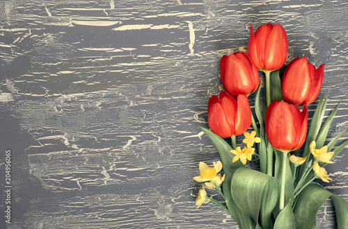 Bunch of red tulips and lily of the valley flowers on rustic background, space