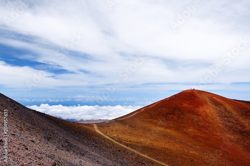 The summit of Mauna Kea, a dormant volcano on the island of Hawaii. Stunningly beautiful red stone peak hovering above clouds, the highest point in the state of Hawaii