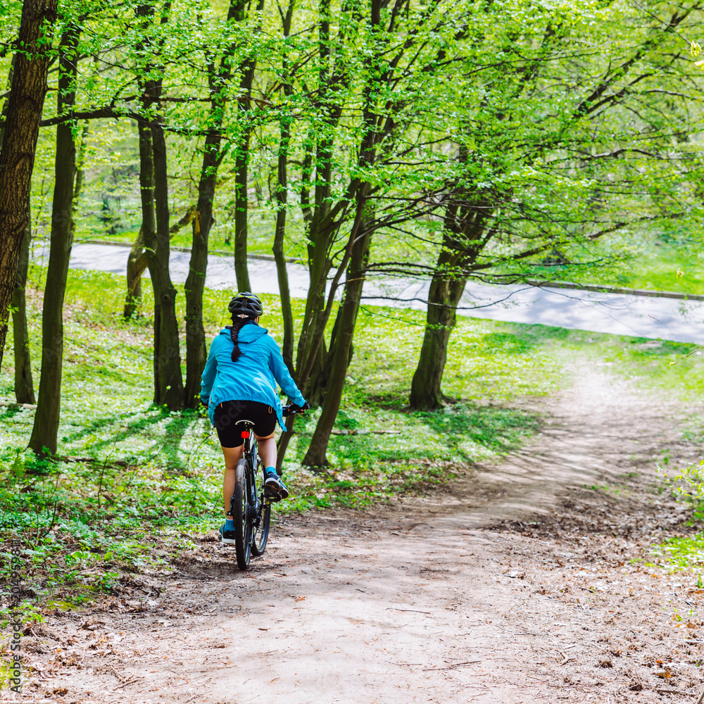 young woman ride bicycle in forest by trail