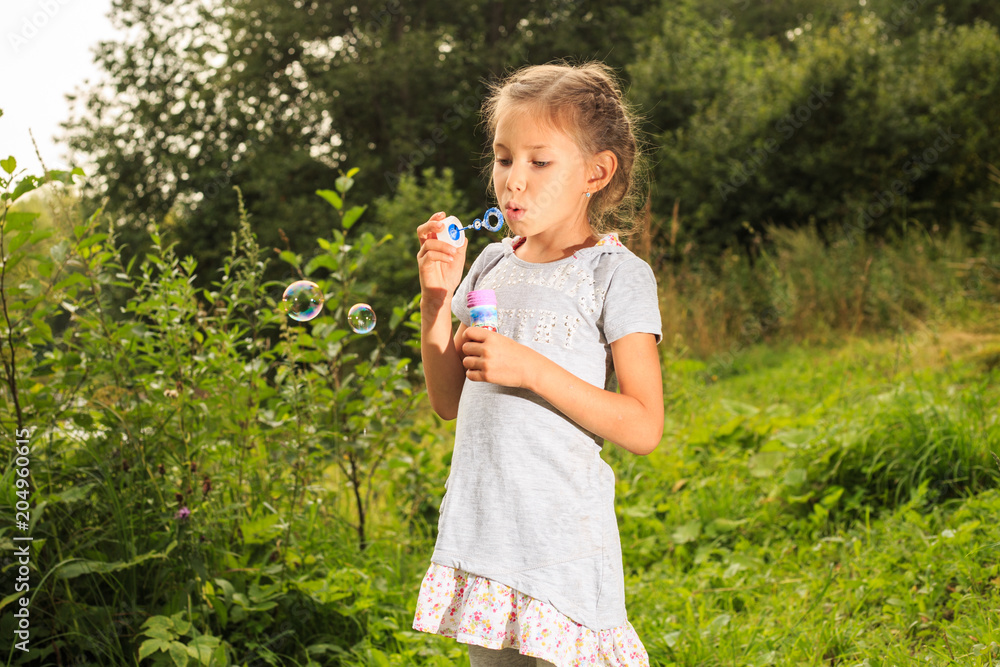 Portrait of funny lovely little girl blowing soap bubbles