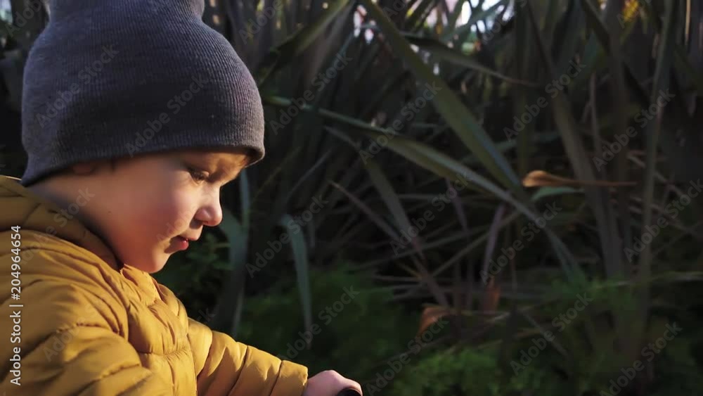 Cute little boy wearing a yellow jacket and a beanie is riding his bike in an empty street. Tracking real time close up shot Cute little boy wearing a yellow jacket and a beanie is riding his bike in an empty street. Tracking real time close up shot