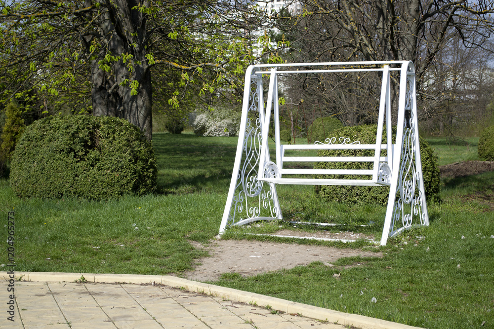 White swing in a green park. White wooden swing outdoor. White swing in a green park. White wooden swing outdoor.