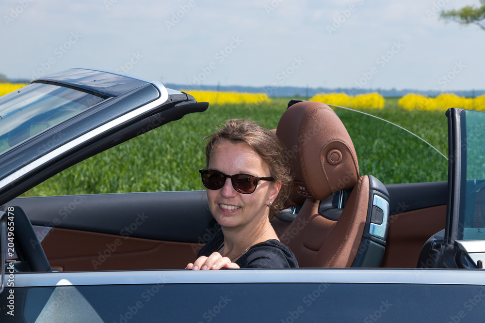 
portrait of a beautiful smiling Brunette Woman Driving in Luxury Convertible Sports Car