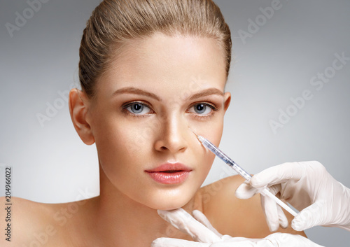 Beautiful woman getting cosmetic injection in eye area from beautician. Clean Beauty concept
