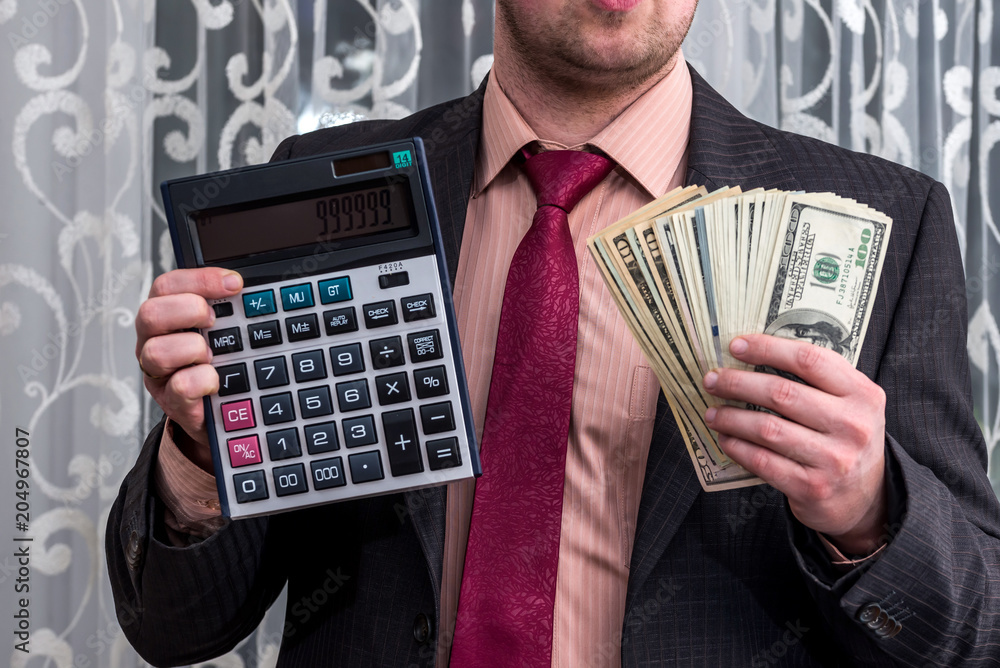 Businessman in suit showing dollar banknotes and calculator