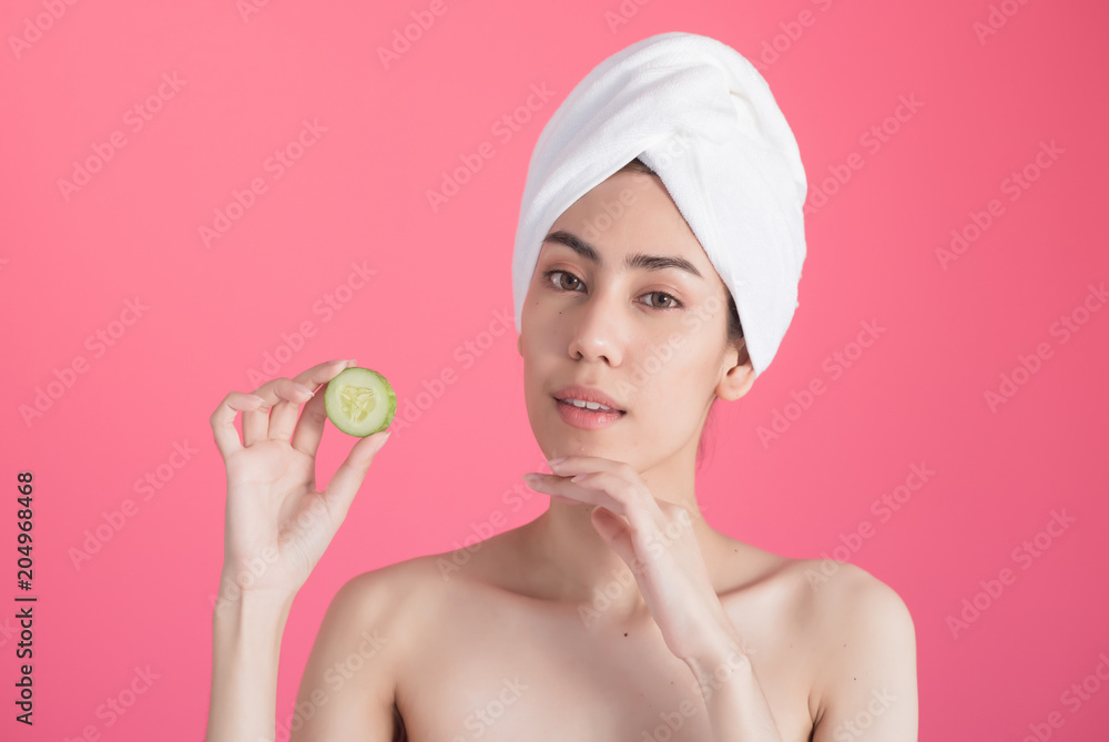 beautiful asia woman with towel on head with perfect clean skin smiling holding cucumber slices over pink background. Beauty cosmetology and spa. beautiful asia woman with towel on head with perfect clean skin smiling holding cucumber slices over pink background. Beauty cosmetology and spa.