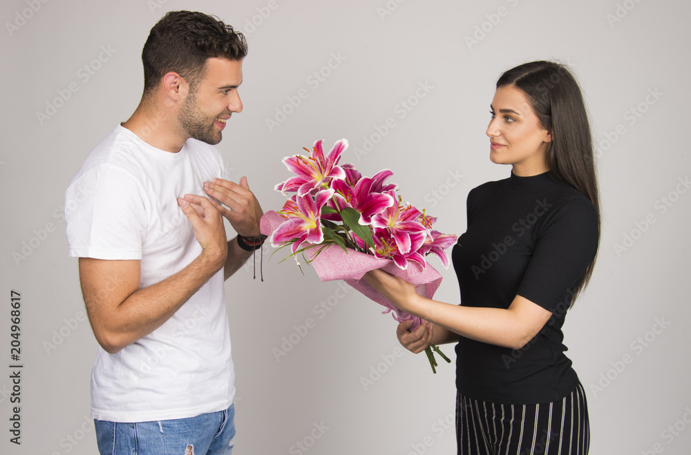 Girl giving flowers to her boyfriend, couple celebrating special occasion concept Girl giving flowers to her boyfriend, couple celebrating special occasion concept