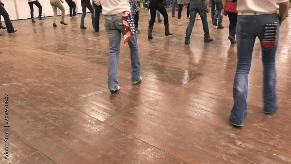 Western dancers dancing together a choreography at a country folk festival. Denim, cowboy boots and USA flag. Learning line dance, bluegrass music, hoedown party and tradition of America Western dancers dancing together a choreography at a country folk festival. Denim, cowboy boots and USA flag. Learning line dance, bluegrass music, hoedown party and tradition of America