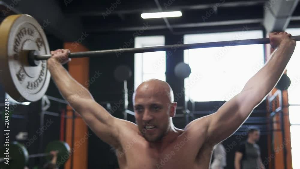 Sweaty fitness man doing barbell snatch exercise in gym Sweaty fitness man doing barbell snatch exercise in gym