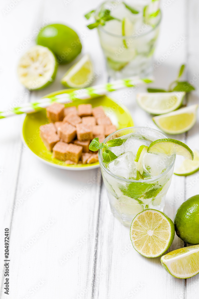 Summer refreshing cocktail caipirinha with lime and mint on white wooden vintage background.