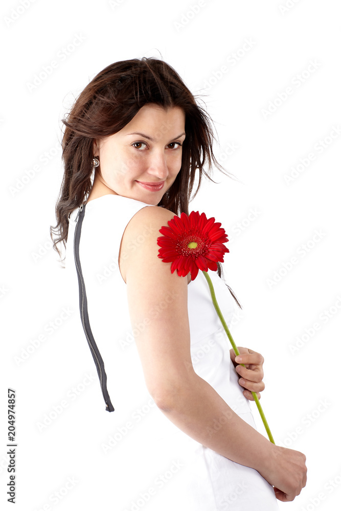 Beautiful young woman in white dress, posing sideways with red flower and looking at camera