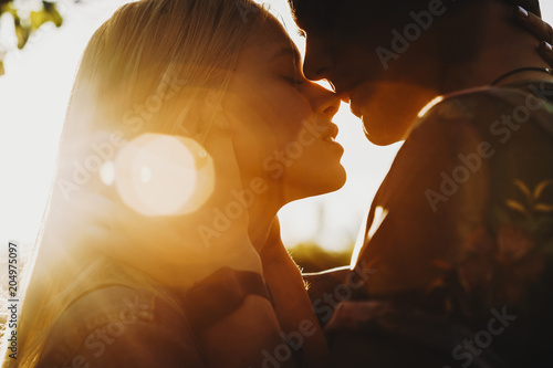 Close up portrait of a beautiful young couple waiting to kiss in their traveling time against sunset light. photo