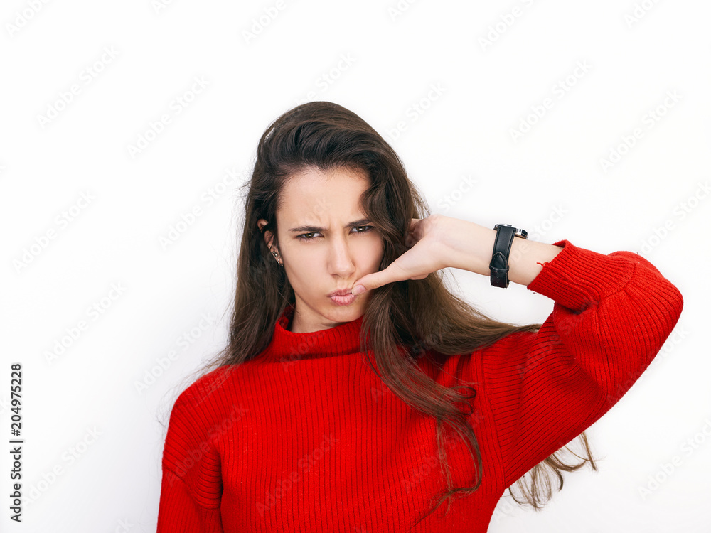 Young beautiful brunette woman in red sweater showing suspicious emotion posing against white background Young beautiful brunette woman in red sweater showing suspicious emotion posing against white background