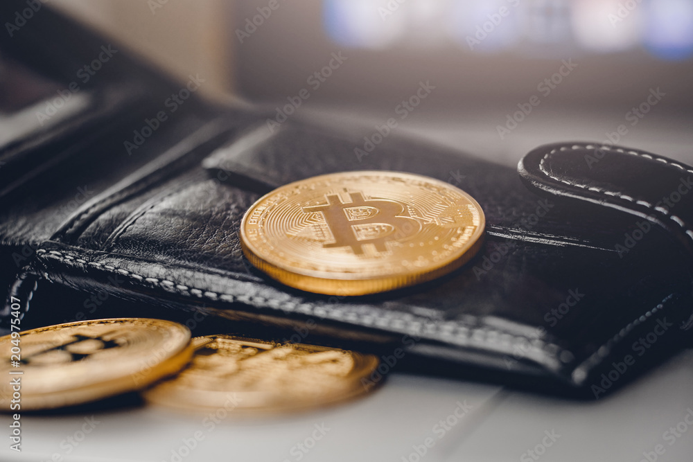 Gold Bitcoin against background of black wallet, concept of crypto currency.