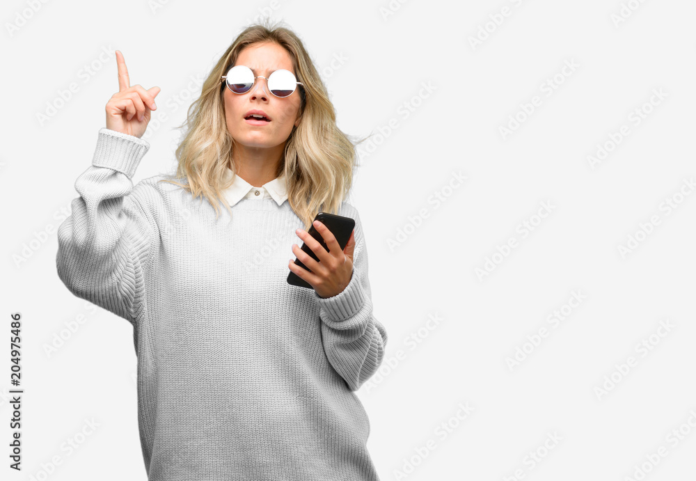 Young beautiful woman using smartphone happy and surprised cheering expressing wow gesture pointing up Young beautiful woman using smartphone happy and surprised cheering expressing wow gesture pointing up