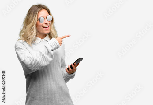 Young beautiful woman using smartphone pointing away side with finger