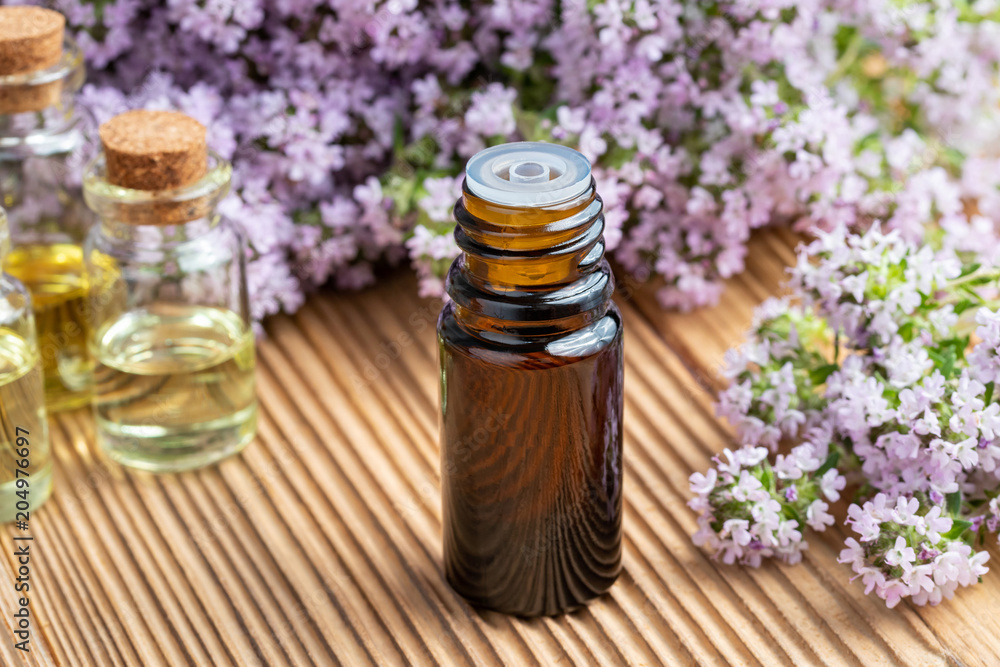A bottle of essential oil with fresh blooming thyme A bottle of essential oil with fresh blooming thyme