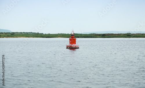 Red navigation buoy on still sea water