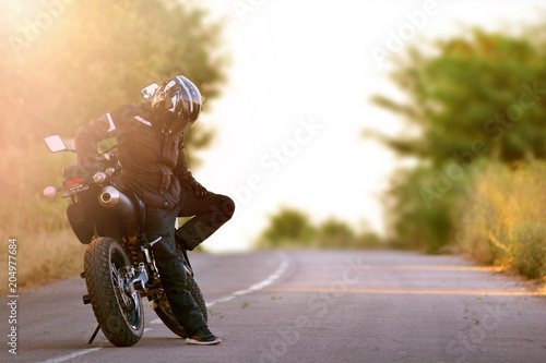 Motorcyclist in helmet thought about and mucked the motorcycle. Motorbike stops on the road. Street lifestyle. photo