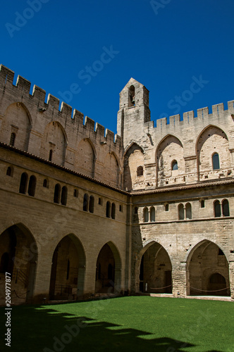 View of courtyard and internal buildings of the Palace of the Popes of Avignon  under a sunny blue sky. Located in the Vaucluse department  Provence-Alpes-C  te d Azur region  southeastern France