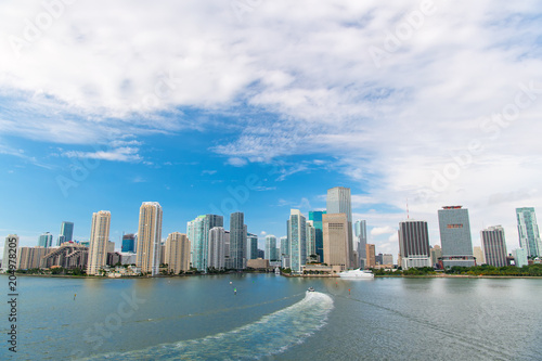 Aerial view of Miami skyscrapers with blue cloudy sky, boat sail © be free
