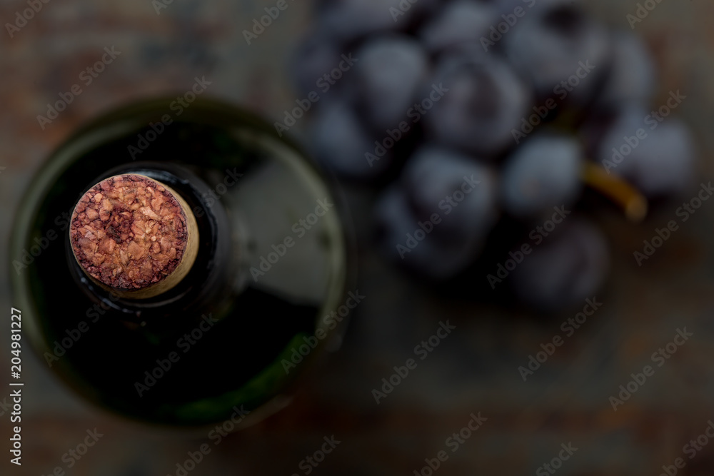 Top view of red wine bottle. Macro selective focus on wine cork. Wine bottle, wine glass and grape on vintage background. Copi space, wine concept