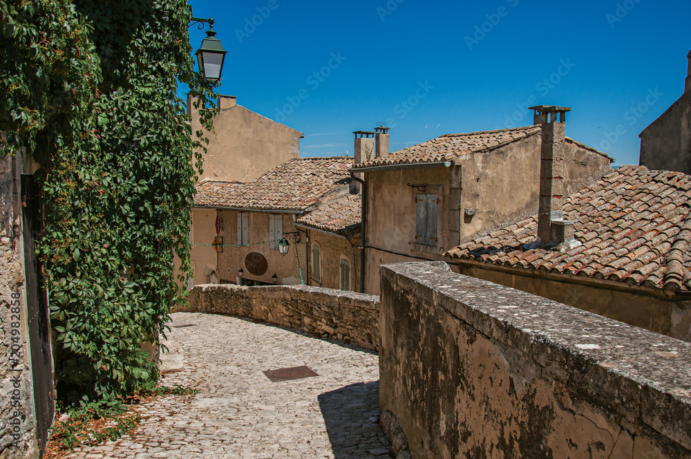 View of typical stone houses with sunny blue sky, in an alley of the historical village of Menerbes. Located in the Vaucluse department, Provence-Alpes-Côte d'Azur region, southeastern France View of typical stone houses with sunny blue sky, in an alley of the historical village of Menerbes. Located in the Vaucluse department, Provence-Alpes-Côte d'Azur region, southeastern France